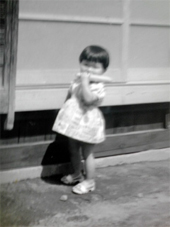 北海道の家の前でとうきびにかぶりつく2歳の頃のRN.折鶴蘭さん。