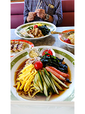 冷麺 奥にオジサンとチャーハンが写っている写真